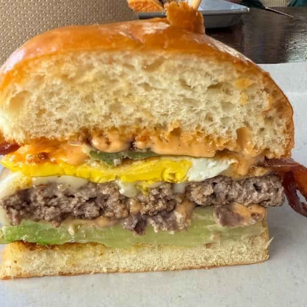 Cross-section of a Bunz burger with egg, bacon, avocado, and special sauce on a brioche bun.