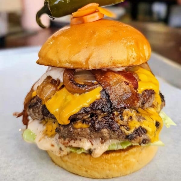A Bunz Handcrafted Burger with two patties, melted cheese, caramelized onions, and a jalapeño on top.